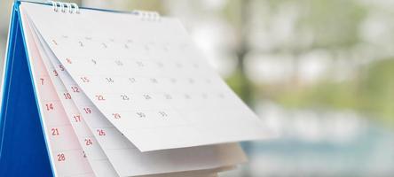 Close up white paper desk calendar with blurred bokeh background appointment and business meeting concept photo