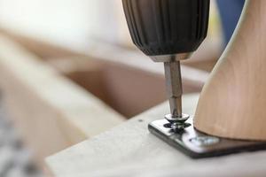 man assembling sofa furniture at home using cordless screwdriver photo