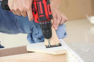 man assembling sofa furniture at home using cordless screwdriver photo