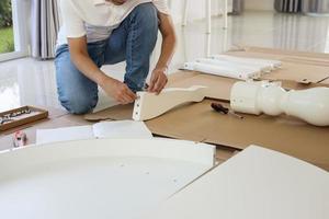 hombre montando muebles de mesa blancos en casa foto