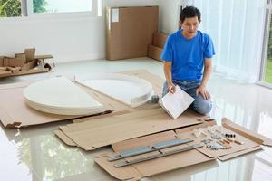 Man assembling white round table furniture at home photo