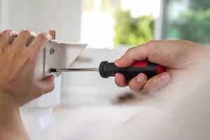 Asian man assembling white table furniture at home photo