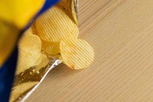 crispy potato chips in snack bag on wood table photo