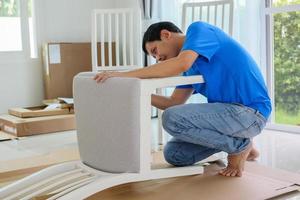 Man assembling white chair furniture at home photo