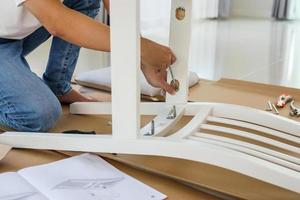 hombre montando muebles de silla blanca en casa foto