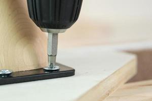 man assembling sofa furniture at home using cordless screwdriver photo