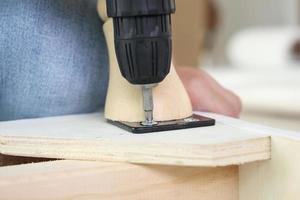 man assembling sofa furniture at home using cordless screwdriver photo