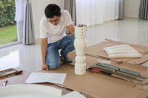 Man assembling white table furniture at home photo