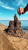 il tipo costruisce un' sabbia castello su il riva del mare video