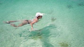 slank vrouw in een zwempak zwemt in een Doorzichtig zee Aan een zonnig dag. zomer vakantie concept. langzaam beweging.
