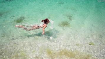 mujer delgada en traje de baño nada en un mar claro en un día soleado. concepto de vacaciones de verano. camara lenta. video