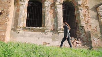 belle fille athlétique marchant le long des anciens bâtiments en ruine. ralenti. prise de vue au steadicam