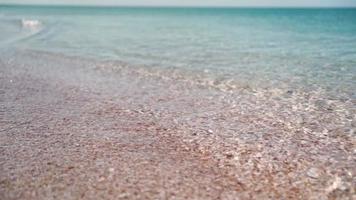 Close-up Beach and Clear Turquoise Sea on a Sunny Day. Sea Water Washes the Shore. Summer Vacation Concept. Slow motion. video