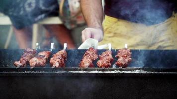 giri un' barbecue spiedo su il griglia. bbq cucinando. il Fumo a partire dal il carne e fuoco. picnic. avvicinamento, lento movimento. video