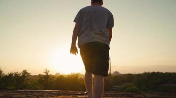 gelukkig Mens wandelingen naar de rand van de dak en verhoogt zijn handen naar de kanten. motiverende video en vrijheid. langzaam beweging