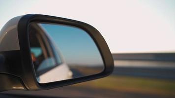 vista de lado espelha o interior de um carro dirigindo ao longo da estrada em um dia ensolarado. conceito de veículos e transporte. ninguém. video