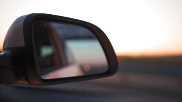 Visualizza a partire dal di il lato specchio il dentro di un' guida auto lungo il autostrada nel un' soleggiato giorno. concetto di veicoli e trasporto. no le persone. video