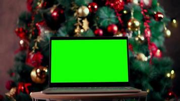 computador portátil de tela verde croma moderno no contexto da árvore de natal - trabalho remoto, conceito de tecnologia. fechar-se. filmagem 4k de alta qualidade video