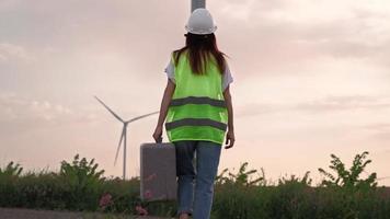 une femme spécialiste de l'écologie professionnelle en uniforme avec un équipement spécial à la main va entretenir un moulin à vent. énergie alternative et renouvelable. technologie moderne. concept d'électricité verte. video