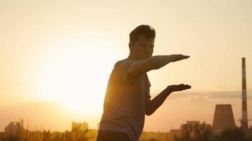 silhouette d'un homme pratiquant les arts martiaux sur fond d'un beau coucher de soleil. le gars s'entraîne au tai-chi et au karaté. art de l'auto-défense. ralenti