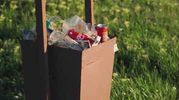 papelera desbordante al aire libre a la luz del atardecer. concepto de contaminación ambiental. residuos plásticos. video