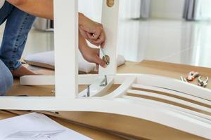 Man assembling white chair furniture at home photo