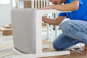 Man assembling white chair furniture at home photo