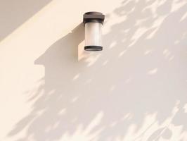 Outdoor cylinder lamp with tree leaves shadow on concrete wall photo