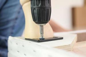 man assembling sofa furniture at home using cordless screwdriver photo