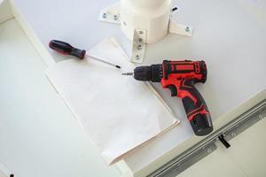 Cordless screwdriver on wood table assembly furniture concept photo