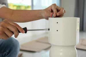 Asian man assembling white table furniture at home photo