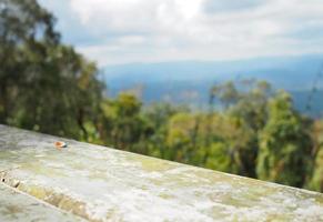 The iron table is empty on the background of forest, mountain and sky. photo