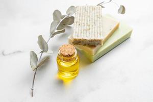 Natural handmade organic soap bars stack on white background with euacalyptus leaves and essential oil. Natural organic cosmetics. photo