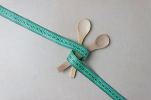 Two wooden spoons tied with measuring tape on the kitchen table. Two wooden spoons tied with measuring tape Minimalism photo