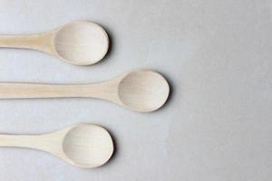 Three empty wooden spoons in the left side of the photo. Close up top view photo. With copy space. Eco kitchenware photo