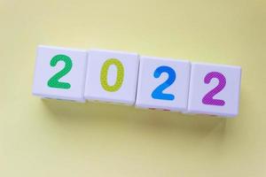 Cubes with colorful numbers 2022 on yellow background. New year, calendar. Figures in a row photo