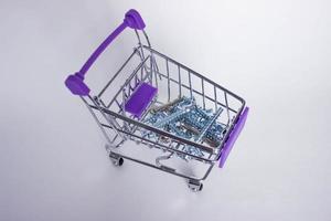 Shopping cart with metal screws on white background photo