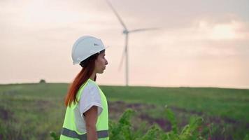 vrouw professioneel ecologie specialist in uniform met speciaal uitrusting in hand- gaat naar onderhoud een windmolen. alternatief en hernieuwbaar energie. modern technologie. groen elektriciteit concept. video