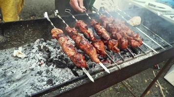 tourne une brochette de barbecue sur le gril. cuisson au barbecue. la fumée de la viande et du feu. pique-nique. gros plan, ralenti. video