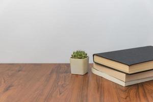 Stack of books and cactus plant on wooden table photo