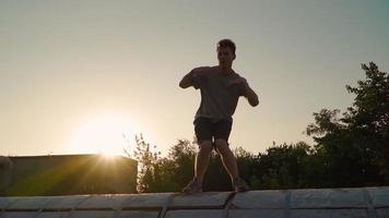 Happy man is dancing funny on the background of a beautiful sunset. Slow motion video