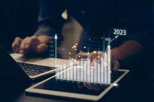 financial charts and graph analysis marketing showing growing revenue In 2023 floating above digital screen tablet, business about strategy for growth and success. photo