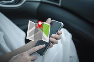 mujer sosteniendo un teléfono inteligente con pantalla táctil de mano y revisando el mapa de navegación gps en el automóvil. foto