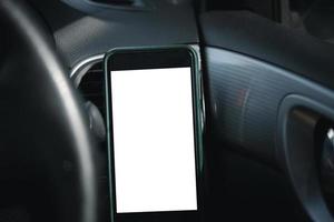 teléfono móvil en la ventilación del coche, en blanco con pantalla blanca, simulacro de teléfono inteligente en el coche. foto