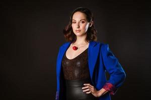 A business woman in a blue jacket poses for the camera on a dark background photo