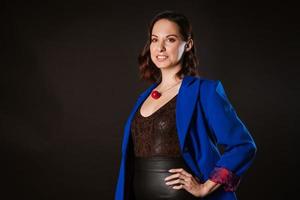A business woman in a blue jacket poses for the camera on a dark background photo
