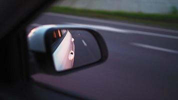 Blick vom Seitenspiegel auf das Innere eines fahrenden Autos entlang der Autobahn an einem sonnigen Tag. Konzept von Fahrzeugen und Transport. keine Leute. video