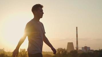 een koel Mens wandelingen tegen de backdrop van een mooi zonsondergang. langzaam beweging video