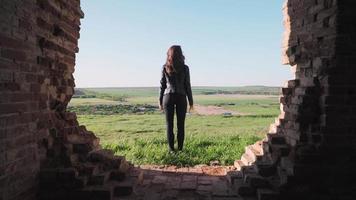 A young woman stands amid the beautiful scenery of green fields and raises his hands up. The joy of victory. Motivational video. Slow motion. Shooting on the Steadicam video