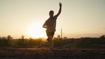 Silhouette eines Mannes, der Kampfkünste auf dem Hintergrund eines wunderschönen Sonnenuntergangs praktiziert. der Typ trainiert Tai Chi und Karate. Kunst der Selbstverteidigung. Zeitlupe video